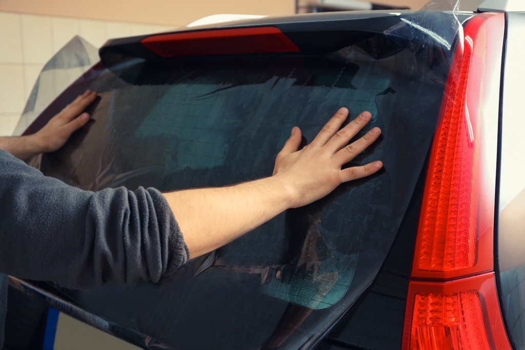man tinting his car windows