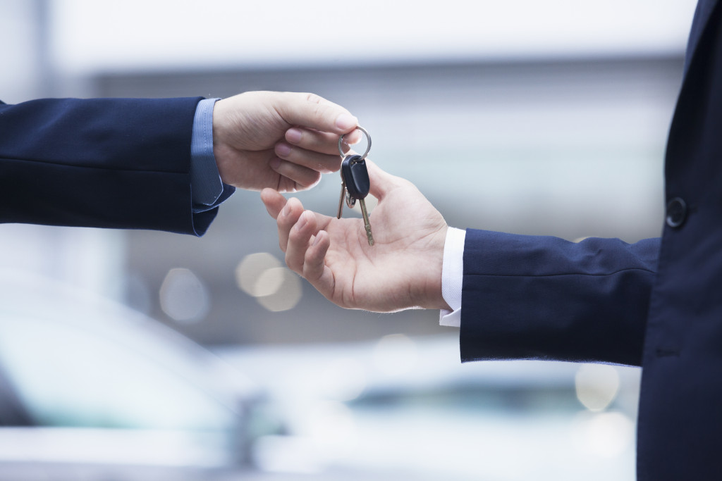 A close-up of a man's hand handing over the keys to a car