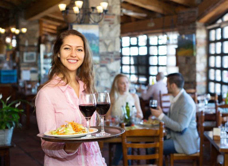 a woman holds a tray of food in a rustic restaurant