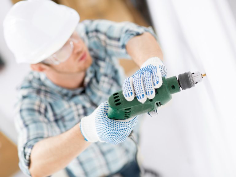 A renovation business owner doing work with a drill